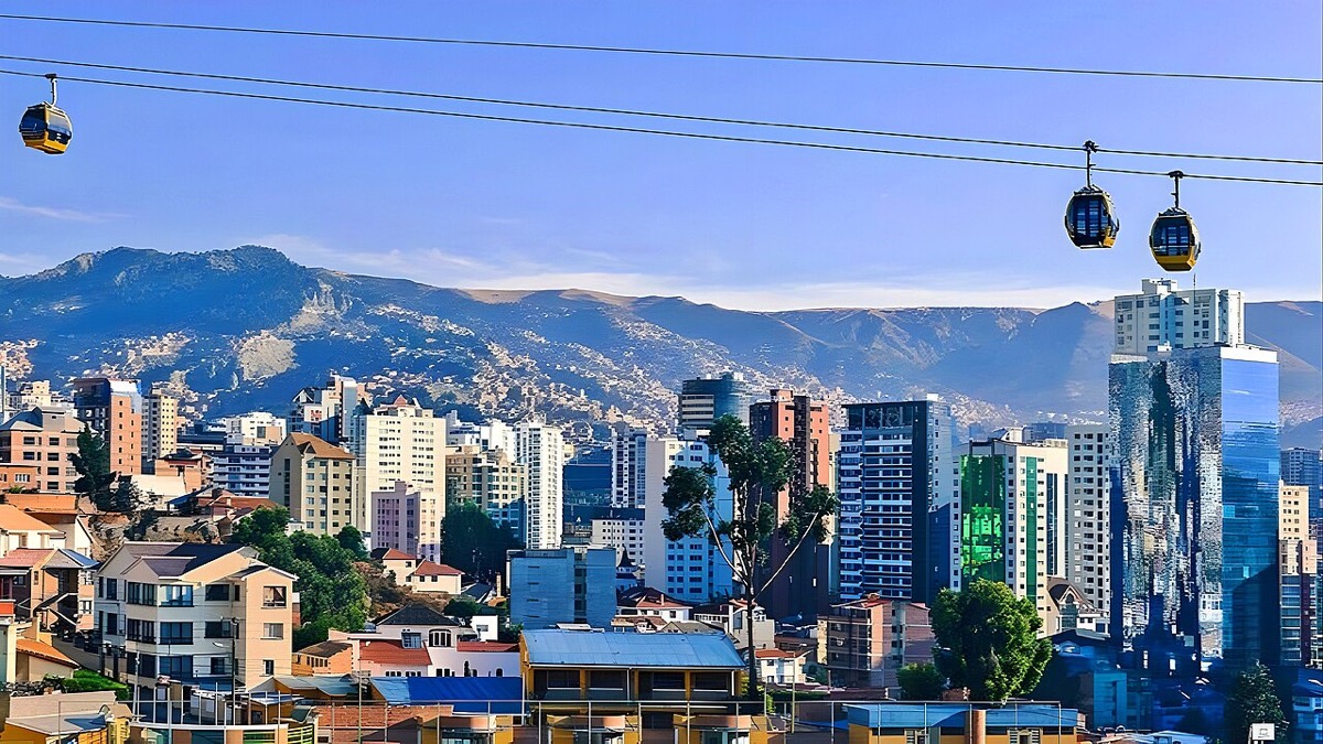 Edificios altos de Sopocachi con cabinas del teleférico pasando por encima y los cerros detrás